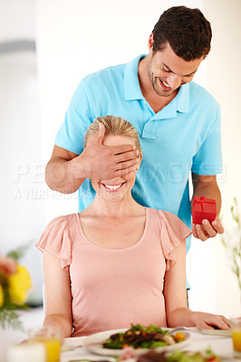 Buy stock photo A handsome man covering his girlfriend's eyes from behind while he hands her a ring box