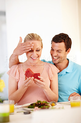 Buy stock photo A beautiful woman looking pleasantly surprised as she opens a jewellery box given to her by her boyfriend