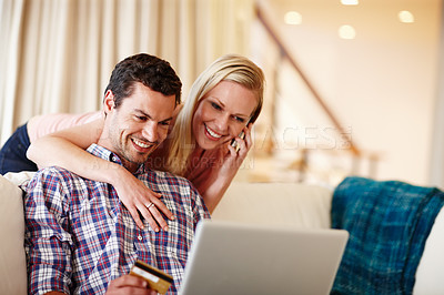 Buy stock photo A beautiful woman hugging her husband from behind while he sits on the couch working on his laptop