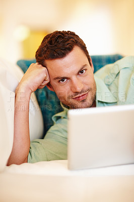 Buy stock photo A handsome man relaxing on the couch with his digital tablet