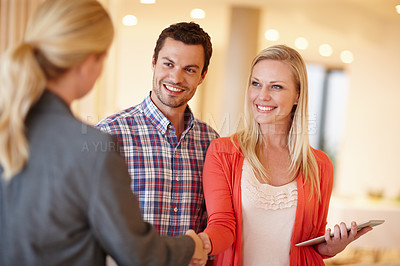 Buy stock photo A happy couple shaking hands with their financial consultant in their home