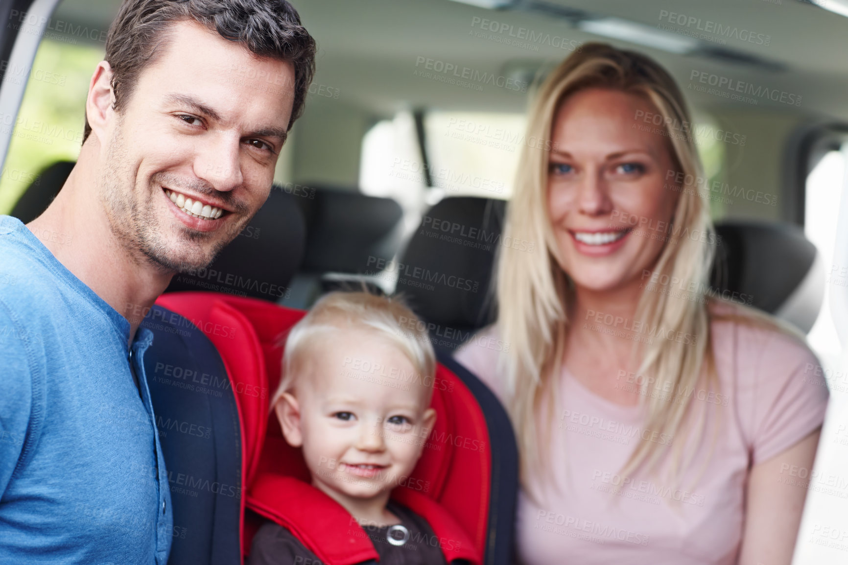 Buy stock photo Portrait of a smiling father and mother next to their toddler who is sitting in his baby seat