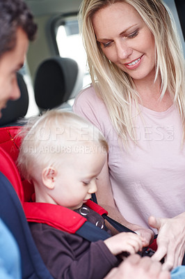 Buy stock photo A  mother and father helping their child in a baby seat for the car