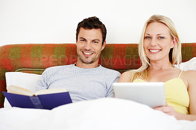 Buy stock photo A young couple relaxing together in bed