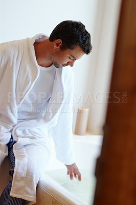 Buy stock photo Man, hygiene and sitting by bath for washing body with skincare, check water and morning grooming in home. Male person, cleaning and liquid in tub for skin health with wellness, robe and dermatology