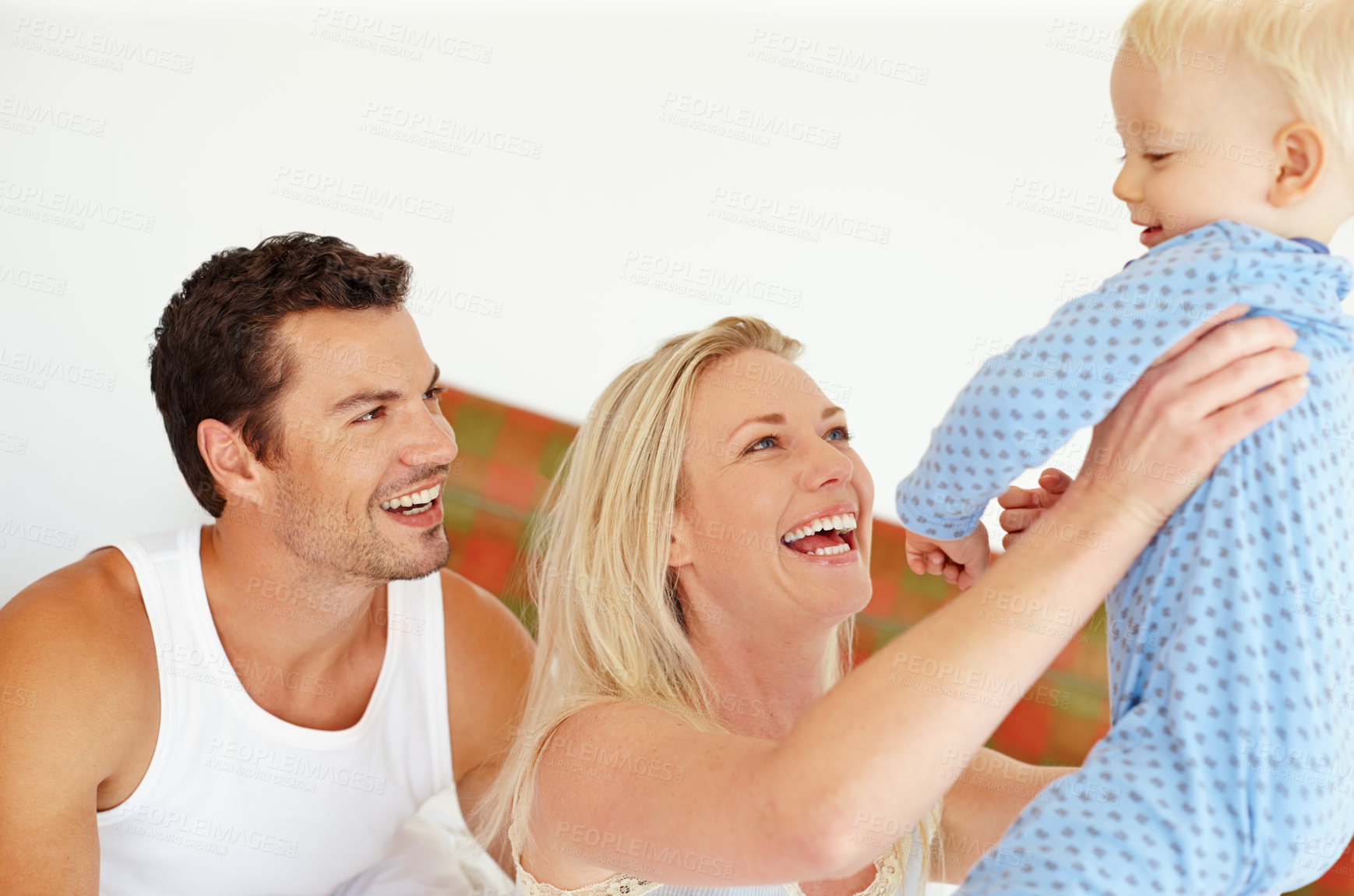 Buy stock photo Happy, love or parents lifting baby in bedroom with support, bonding and playing morning games at home together. Family, learning or people in house with security, trust or care for child development