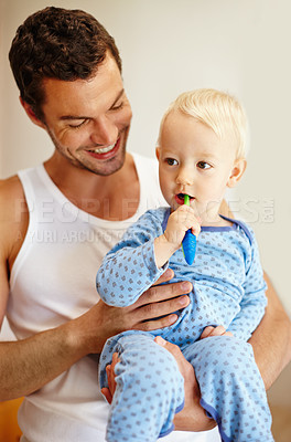 Buy stock photo A little boy brushing his teeth while sitting on his dad's lap