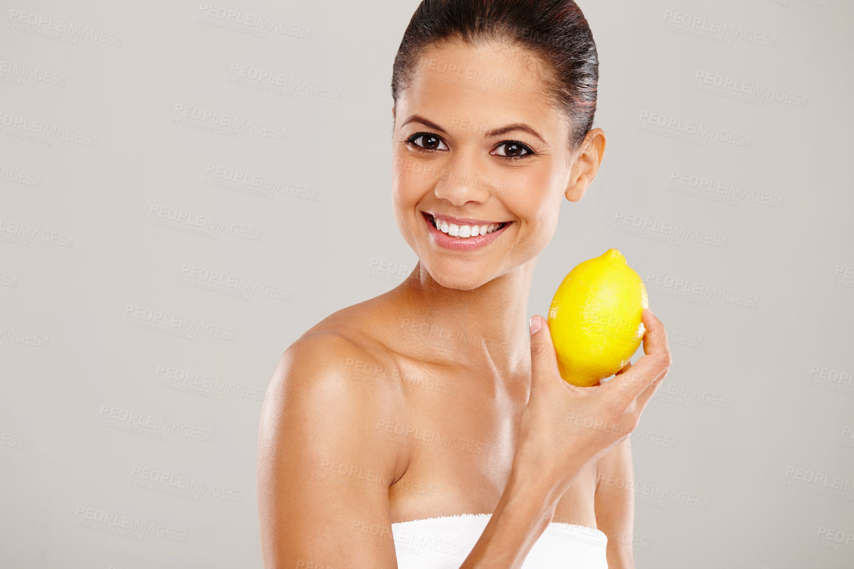 Buy stock photo Cropped portrait of a smiling woman holding up a fresh lemon - isolated