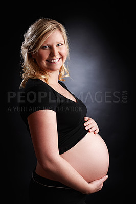 Buy stock photo Woman, portrait and pregnancy with smile from healthy baby growth, love and pregnant stomach in studio. Mother, wellness and holding abdomen with confidence and belly support with black background