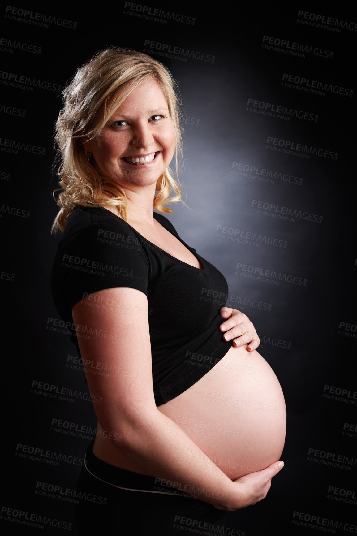 Buy stock photo Woman, portrait and pregnancy with smile from healthy baby growth, love and pregnant stomach in studio. Mother, wellness and holding abdomen with confidence and belly support with black background