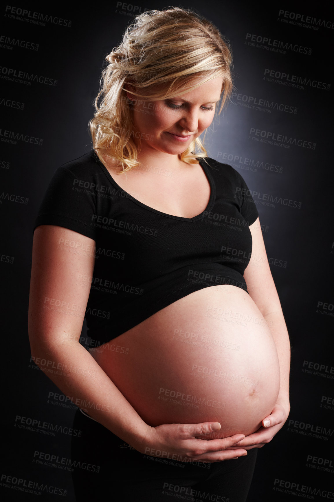 Buy stock photo Pregnant, woman and happy with stomach in studio, baby bump and expectant mother smile for pregnancy. Black background, gestation period and gynecology or glowing, maternity and love for unborn kid