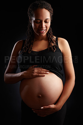 Buy stock photo Pregnant, woman and smile with stomach in studio, baby bump and expectant mother happy for pregnancy. Black background, gestation period and gynecology or glowing, maternity and love for unborn kid