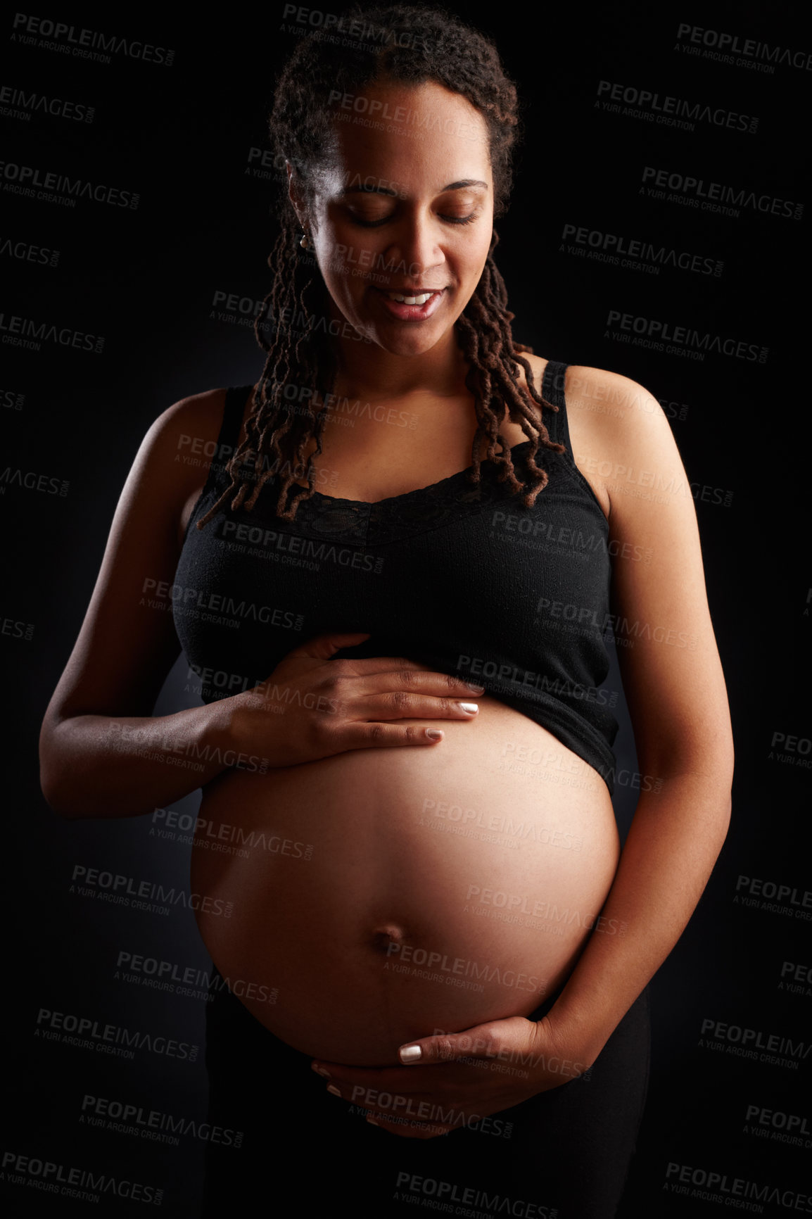 Buy stock photo Pregnant, woman and smile with stomach in studio, baby bump and expectant mother happy for pregnancy. Black background, gestation period and gynecology or glowing, maternity and love for unborn kid