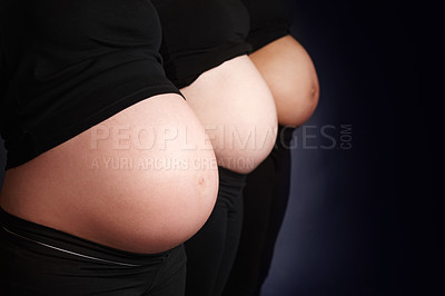 Buy stock photo Women, pregnant and stomach in studio for wellness, community and health or care for child. Support, friends or diversity for mothers by black background and pride for growth and development for baby