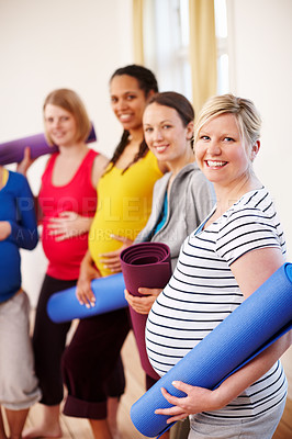 Buy stock photo A multi-ethnic group of pregnant women holding their exercise mats in a gym