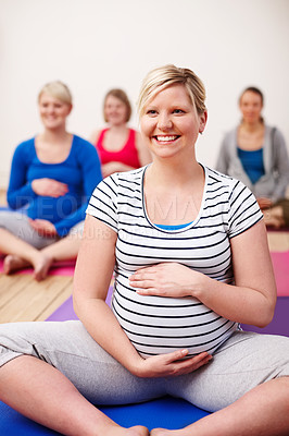 Buy stock photo A group of pregnant women sitting cross-legged in a yoga class and smiling happily