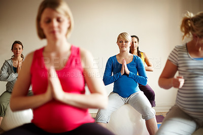 Buy stock photo A multi-ethnic group of pregnant women meditating on exercise balls in a yoga class