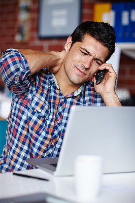Buy stock photo A stressed young entrepreneur rubbing his neck while on the phone to a client