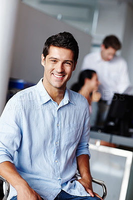 Buy stock photo Portrait of a confident young businessman with his colleagues blurred in the background