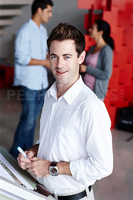 Buy stock photo Portrait of a young architect standing alongside an easel and working on his designs