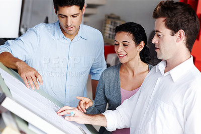 Buy stock photo Three talented architects working on design blueprints together