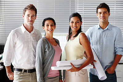 Buy stock photo A confident team of architects smiling at you while holding blueprints