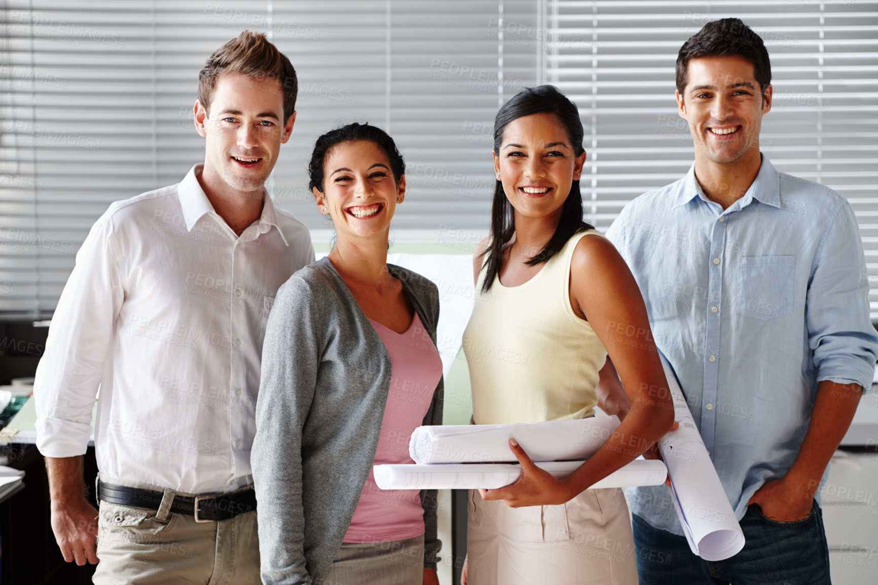 Buy stock photo A confident team of architects smiling at you while holding blueprints