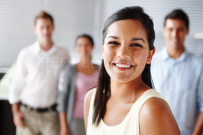 Buy stock photo Portrait of a pretty young businesswoman smiling with her team blurred in the background