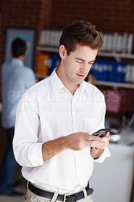 Buy stock photo A handsome young businessman sending a text message