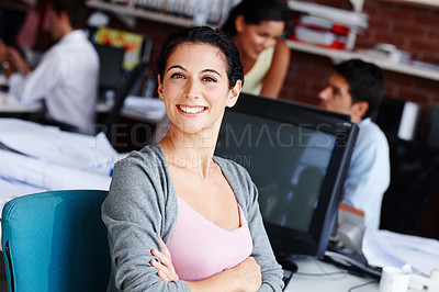 Buy stock photo A pretty businesswoman sitting at her desk with her colleagues blurred in the background