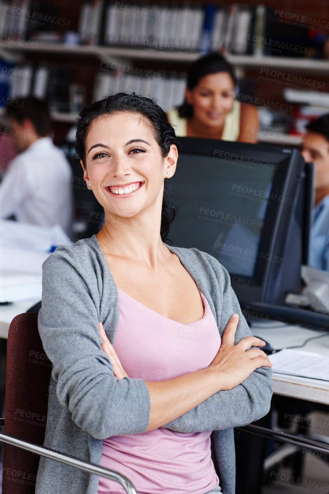 Buy stock photo A pretty businesswoman sitting at her desk with her colleagues blurred in the background