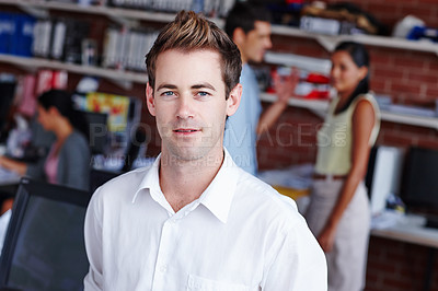 Buy stock photo Portrait of a confident young businessman and his colleagues blurred in the background