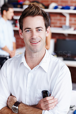 Buy stock photo A handsome young businessman smiling at you while his colleagues work in the background