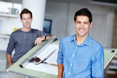 Buy stock photo Two young architects standing beside an easel with their blueprint on it