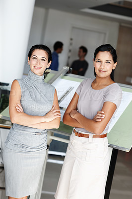 Buy stock photo Two confident architects crossing their arms and standing in front of their blueprints