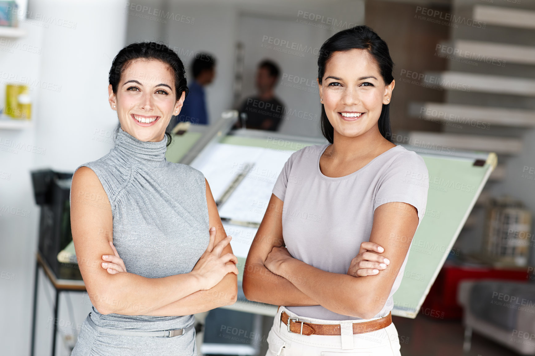 Buy stock photo Two confident architects crossing their arms and standing in front of their blueprints