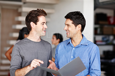 Buy stock photo Two friendly colleagues discussing a business portfolio in the office