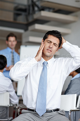 Buy stock photo A pained young businessman dealing with the onset of a migraine