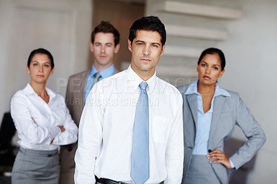 Buy stock photo A young business leader standing in front of his successful team confidently