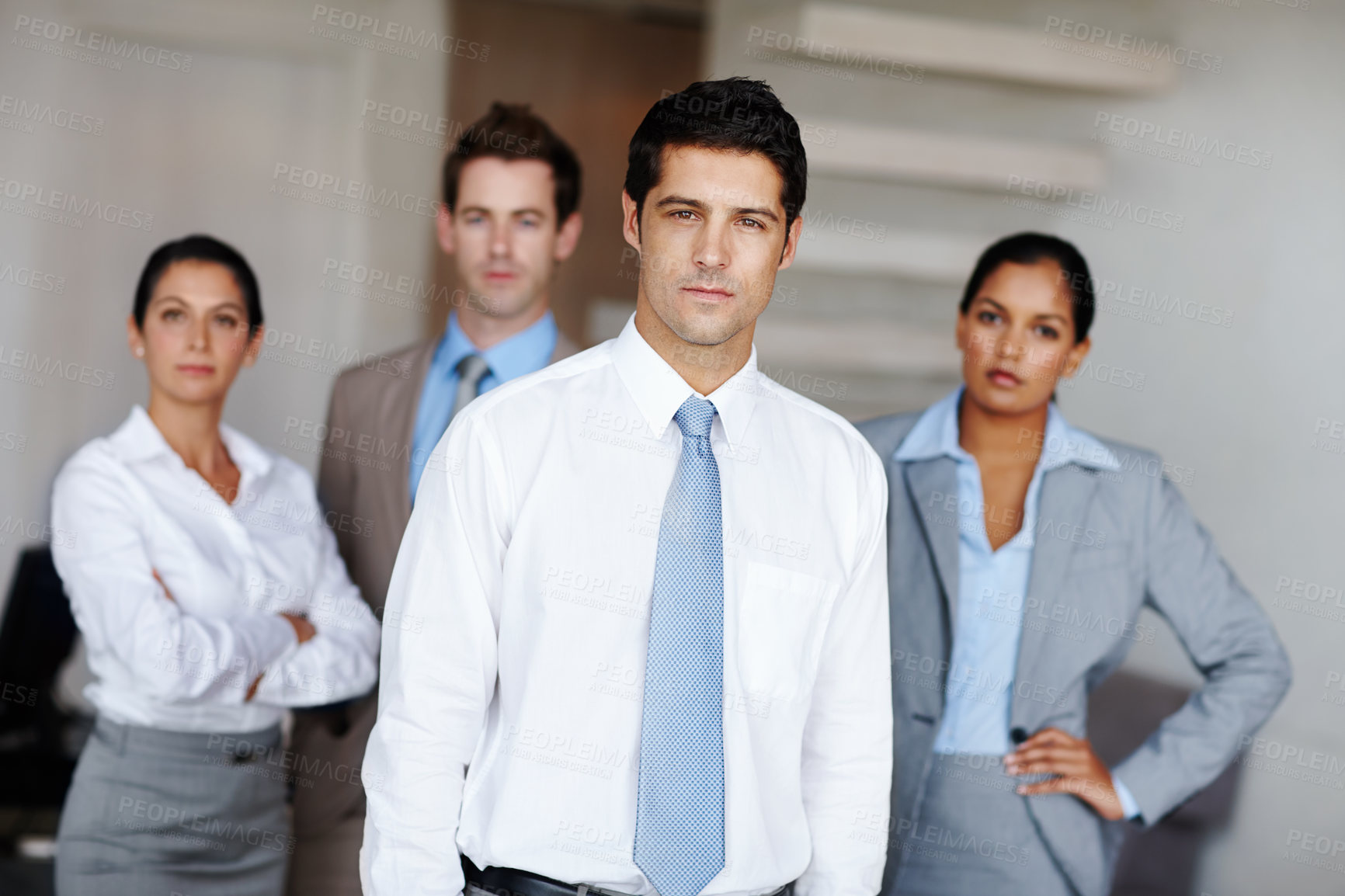 Buy stock photo A young business leader standing in front of his successful team confidently