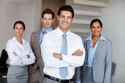 Buy stock photo A young business leader standing in front of his team smiling confidently