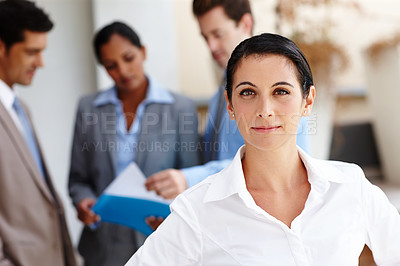 Buy stock photo Portrait of a beautiful young businesswoman with her colleagues blurred in the background