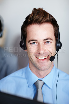 Buy stock photo A handsome young call center agent smiling while sitting at his desk