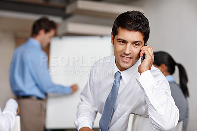 Buy stock photo An angry young executive taking a call during a business presentation