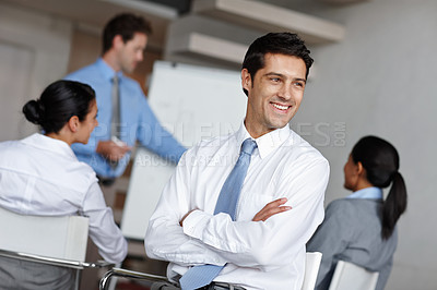 Buy stock photo A handsome young businessman crossing his arms and looking away thoughtfully during a presentation