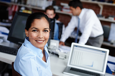 Buy stock photo A pretty young woman glancing over her shoulder while sitting at her workspace