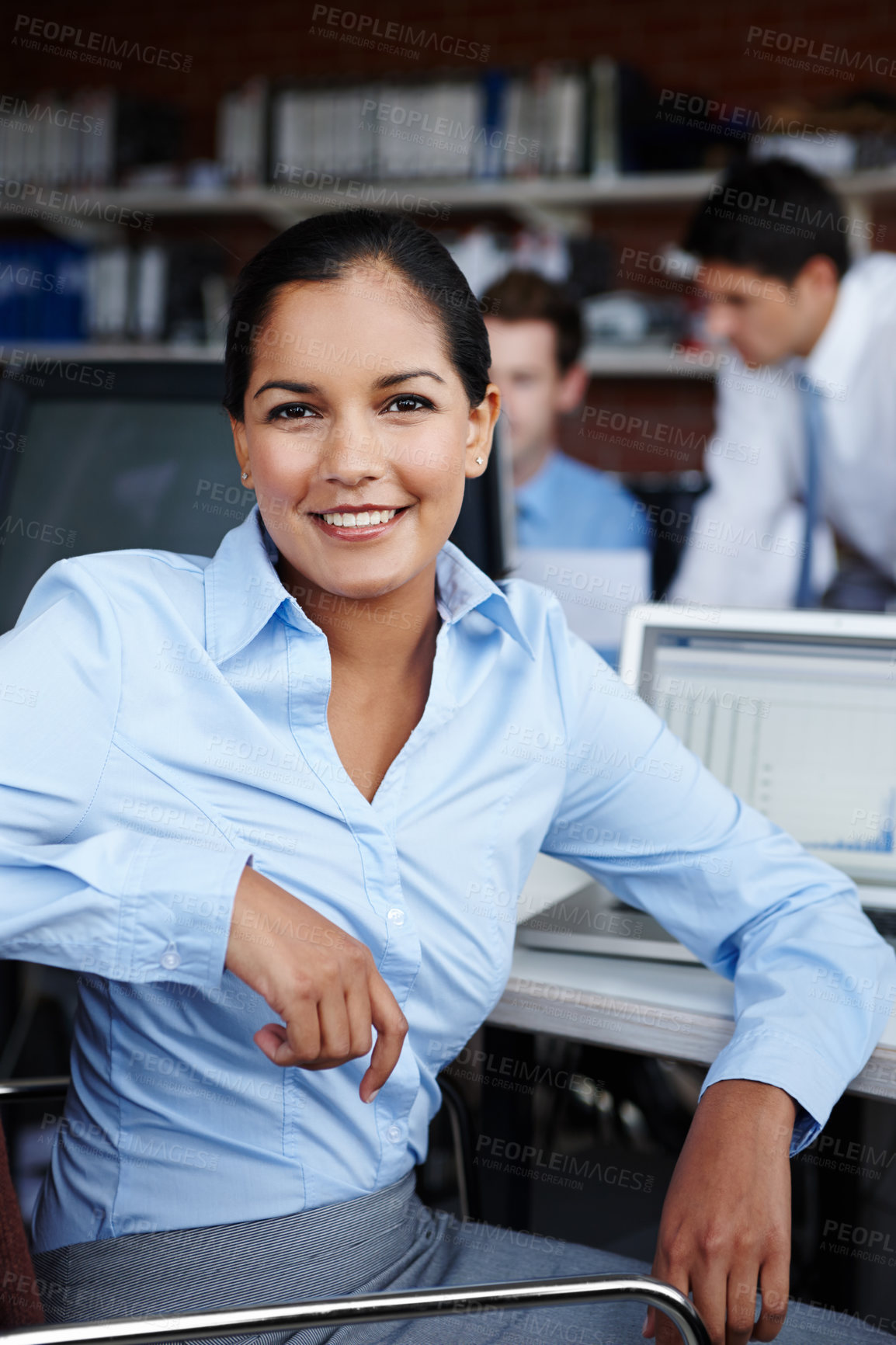 Buy stock photo A pretty young businesswoman turning to look at you while sitting at her workspace