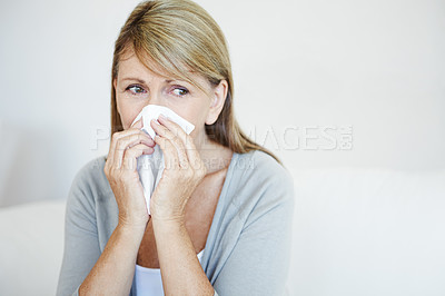 Buy stock photo Mature woman, sick and blowing nose with tissue for virus, cold or flu on sofa at home. Female person with hayfever, sinus or covid symptom for sneeze, respiratory disease or viral infection at house