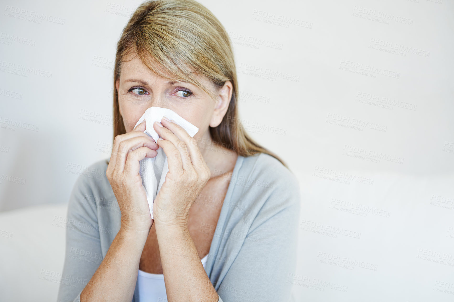 Buy stock photo Mature woman, sick and blowing nose with tissue for virus, cold or flu on sofa at home. Female person with hayfever, sinus or covid symptom for sneeze, respiratory disease or viral infection at house