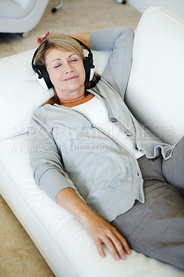 Buy stock photo Mature woman, headphones and relax on sofa in home, living room and smile for listening to radio. Person, music and subscription for audio book, above and streaming with rest on couch in Germany